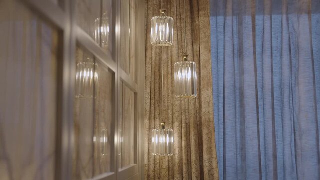 Glowing glass pendant lights besides elegant curtains curtains in luxury real estate interior.