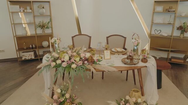 Wedding sweetheart table with pink floral runner inside golden tipi tent with shelving decor