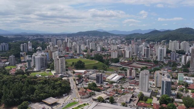 Aerial view of Joinville city with central green park, dense urban skyline and surrounding hills in southern Brazil.