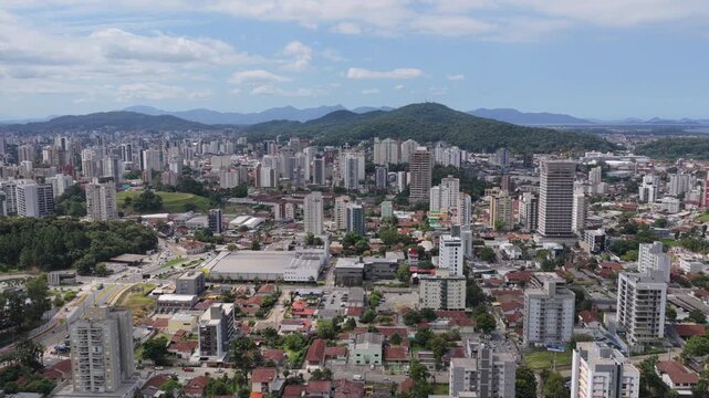 Aerial view of Joinville city with residential and commercial buildings surrounded by green hills in southern Brazil.