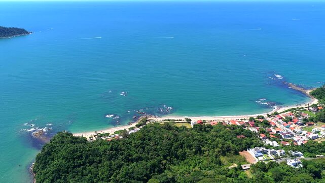 Tropical jungle and residential beach houses at Praia da Bacia da Vov&oacute; and Praia da Saudade in Penha. Downward tracking aerial on sunny day.