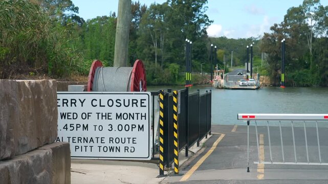 Ferry closure sign in foreground with ferry and river crossing behind.