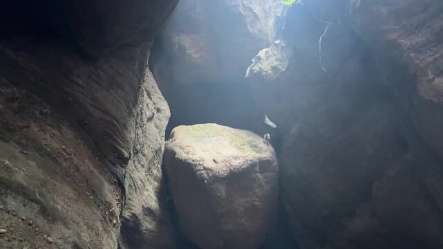 Narrow opening in cave illuminates lake with tip of Lord Shiva's trident visible. Tilt down