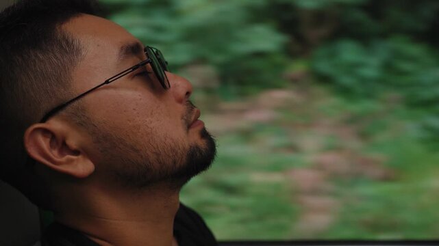 A man sitting by a train window looking outside during a journey. Calm and reflective mood with passing scenery, representing travel, solitude, and contemplation.