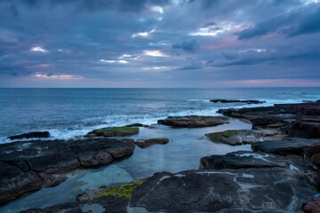 Obraz premium Dark blue ocean waves crash on rocky shore under cloudy sky water crashing waves