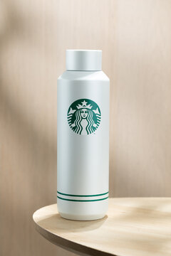 Minimalist insulated bottle with Starbucks logo placed on a wooden table, clean background, modern lifestyle concept, reusable drinkware and eco-friendly trend.