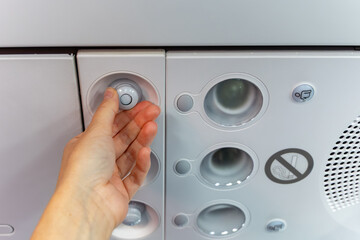 Airplane air conditioning control panel with a hand adjusting the temperature dial, featuring various buttons and indicators in a modern aircraft interior © Kateryna Muzhevska