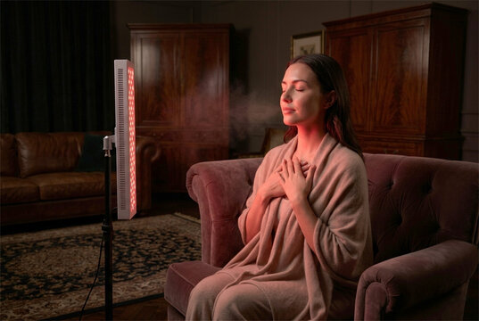 Beautiful young woman experiencing red light therapy at home for skin rejuvenation and wellness.