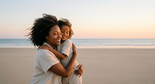 A mother and daughter embrace on a beach at sunset, sharing a moment of love and connection.