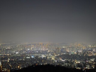 Naklejka premium Panoramic night view of a glowing city skyline from a mountain top at night