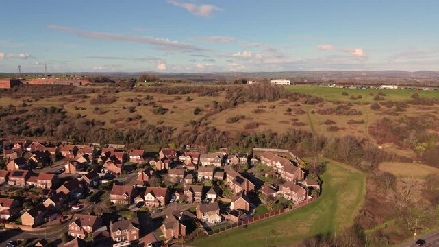 Fort Widley Swanick Hill Portsmouth, flight over housing and hill passing the repurposed military fort looking inland over rolling countryside in bright sunshine with blue sky and wispy clouds