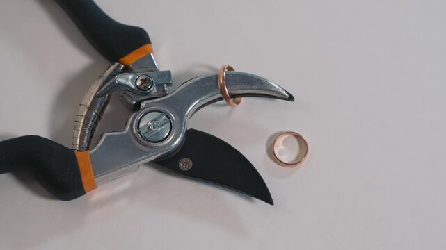Marriage ending concept through rings and cutting tool conveys divorce and emotional crisis