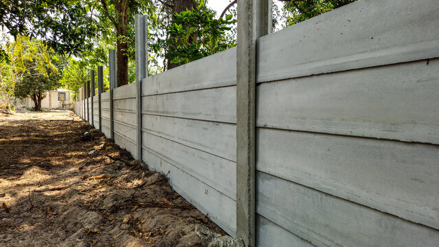High-quality precast concrete fence wall installed on a construction site. Modern prefabricated cement boundary for residential security and industrial property privacy.