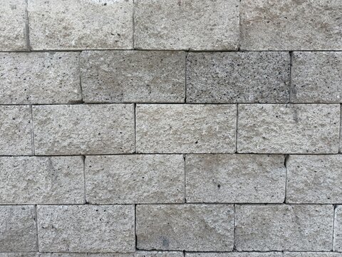 Rugged Gray Volcanic Tuff Stone Wall Texture: Seamless Background of Natural Ashlar Masonry with Weathered Porous Surface, Solid Mineral Blocks for Industrial Architecture and Modern Outdoor Design