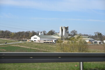 Modern farm with buildings and grain silos under sunny sky in rural landscape  © Miroslaw