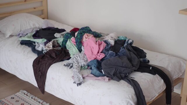 Pile of clothes on bed for laundry day or tidying up mess.