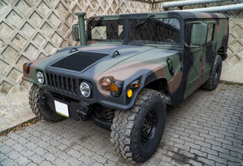 Obraz premium Military Humvee parked on an street, showcasing its rugged design and operational readiness in a secure military base. Khaki camouflage military Hummer front view. HMMWV.