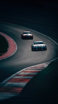 Two race cars navigate a tight chicane on a racetrack, showcasing speed and precision in a thrilling motorsport competition atmosphere