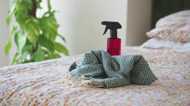 Clean clothes with spray bottle on bed concept for fresh laundry and housework chores.