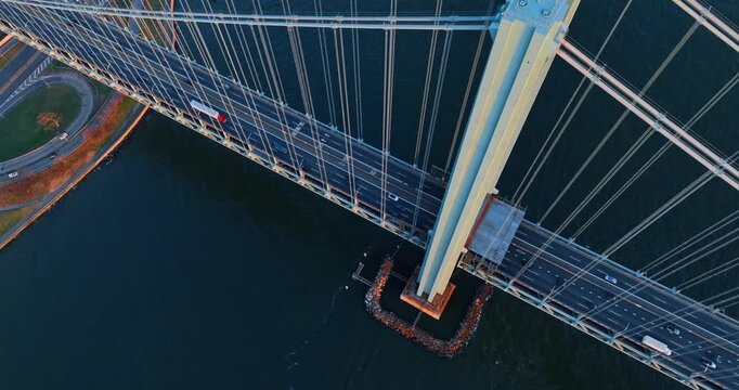Rising along the huge support of the Verrazano-Narrows Bridge. Top view on the multi-lane highway with lively traffic on by the bridge. New York, USA.