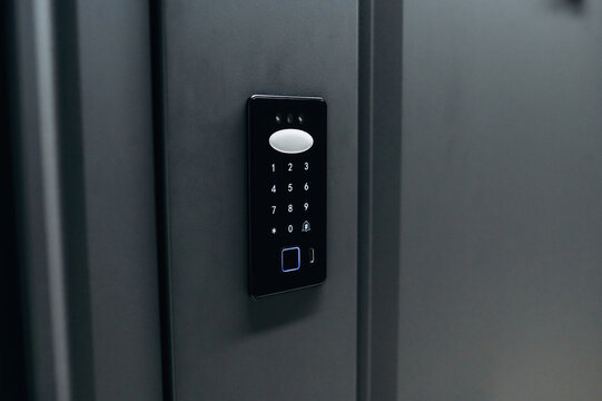 Modern electronic keypad access control system mounted on a sleek black wall, featuring numeric buttons and a fingerprint scanner for secure entry