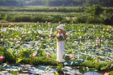 Fotobehang Lotusbloem Woman Holding Lotus Flowers in Tra Ly Lotus Pond Vietnam  © Buyanskyy Production