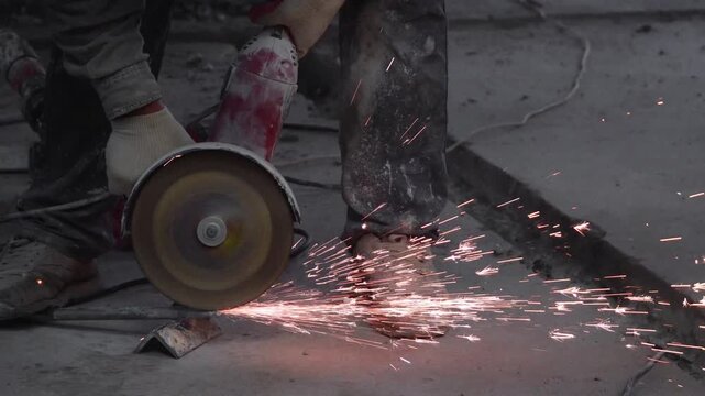 The sides fly bright sparks from the angle grinder machine. A male in a working gloves grinds a metal product with angle grinder. Cutting metal causing sparks isolated - a series of METAL INDUSTRY. 