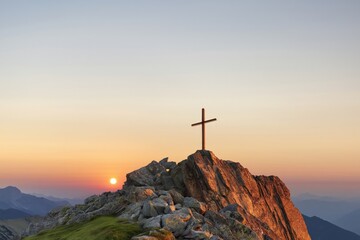 Obraz premium Wooden cross overlooking rocky summit at sunset glow