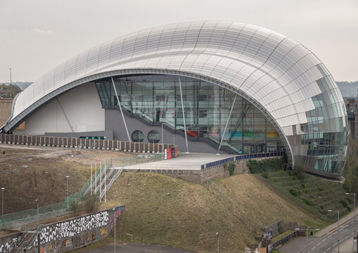 Newcastle, UK - Apr 11, 2025 - The sinuous, stainless-steel canopy of The Glasshouse International Centre (Sage Gateshead) for Music crests like a shimmering glass wave over the industrial landscape. 