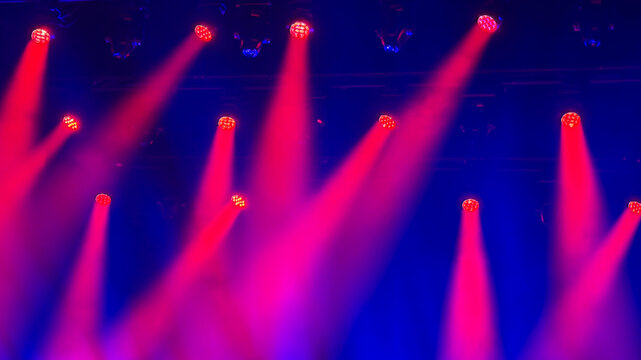 red and pink light beams on blue stage during music concert