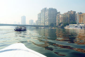 Naklejka premium Beautiful skyline of Cairo reflected in the Nile with boats cruising along the calm waters in the early morning mist