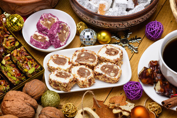 Rich festive table with various Turkish delight lokum nuts black coffee and Christmas decorations on warm wooden background