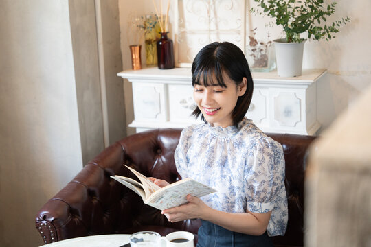 カフェで本を読みながらリラックスしている女性