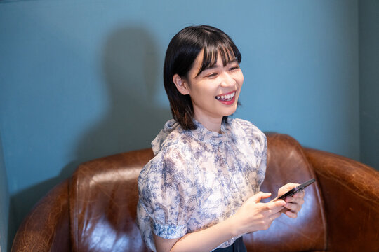 カフェでスマホを持って笑っている女性