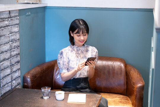 カフェでスマホを見ながらくつろいでいる女性