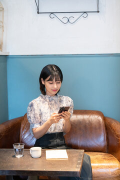 カフェでスマホを見ながらくつろいでいる女性
