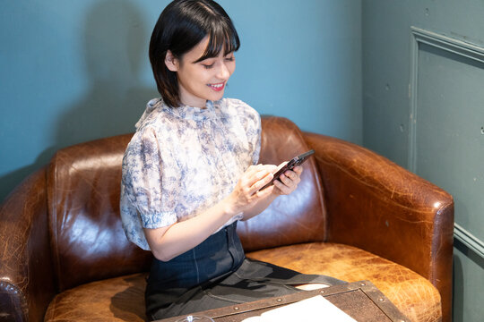 カフェでスマホを見ながらくつろいでいる女性