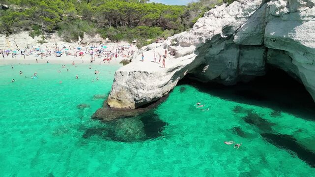 Aerial drone view around Cala Macarella and Macarelleta beach with clean turquoise water, Menorca Island, Balearic islands, Spain. People jumping from the rock cliffs