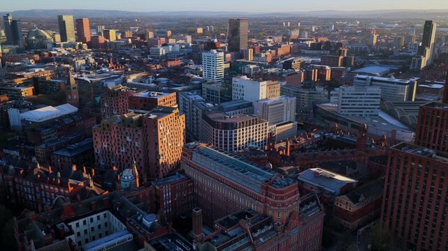 Aerial video of Manchester bathed in golden morning light, highlighting the diverse architecture and the hills on the distant horizon.