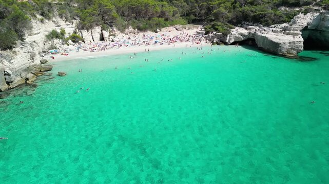 Aerial drone view around Cala Macarella and Macarelleta beach with clean turquoise water, Menorca Island, Balearic islands, Spain. People jumping from the rock cliffs