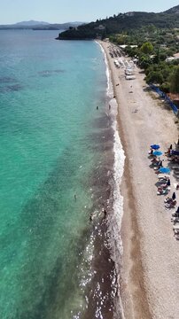 Crystal clear sea water and white pebble shore at Barbati Beach, Corfu. Stunning natural beauty of the Greek islands with scenic mountain views and bright summer sunlight.