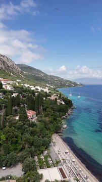 Panoramic 4K view of Barbati Beach in Corfu, Greece. Beautiful sea horizon, calm turquoise waves, and white pebbles, ideal for travel, lifestyle, and nature background.