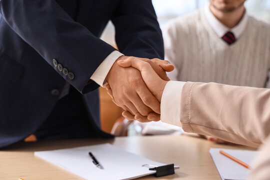 Female business mediator with clients shaking hands at table in office, closeup