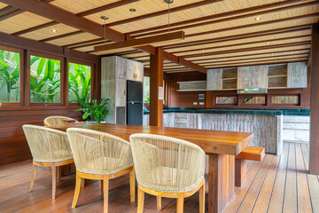 Fototapeta premium A large open kitchen with a wooden dining table and chairs. The chairs are white and the table is made of wood. The kitchen is well-lit and has a warm, inviting atmosphere