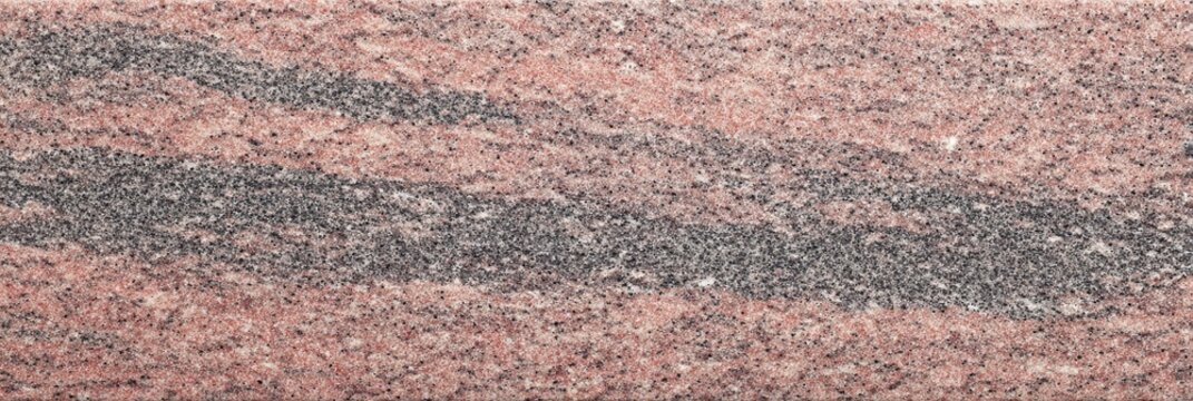 A detailed view of a leathered pink granite stone texture featuring wavy bands of dark grey and black minerals across a speckled reddish surface suitable for background use.