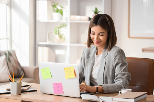 Young businesswoman using laptop to search online at desk in office