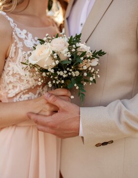 Everlasting Devotion: A couple's hands gently embrace, cradling a delicate bouquet, symbolizing a promise of enduring love and unity. A tender moment, expressing commitment.