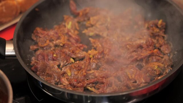 Close-up of meat simmering in frying pan