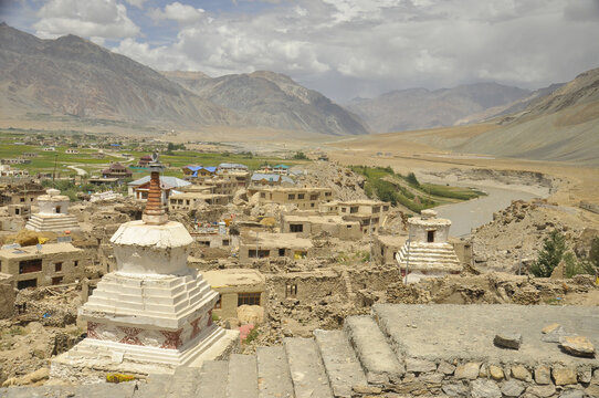 View of a Padum city with new and abandoned buildings with a lake and dry mountains.