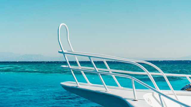 A luxury yatch features a clean blue ocean with a metal ladder and steps for relaxation under the summer sky by the aqua ocean